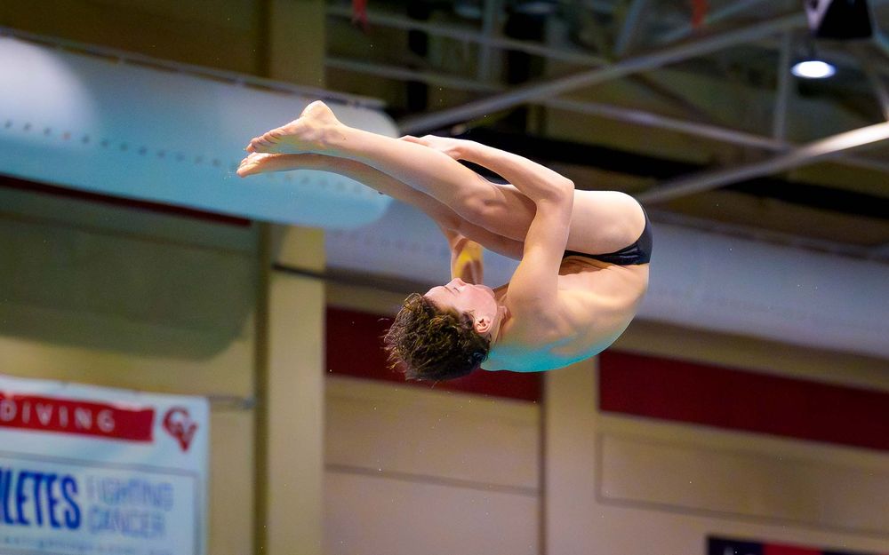 Diver in mid-air performing a flip during the diving competition at the Hershey vs. Cumberland Valley swim meet.