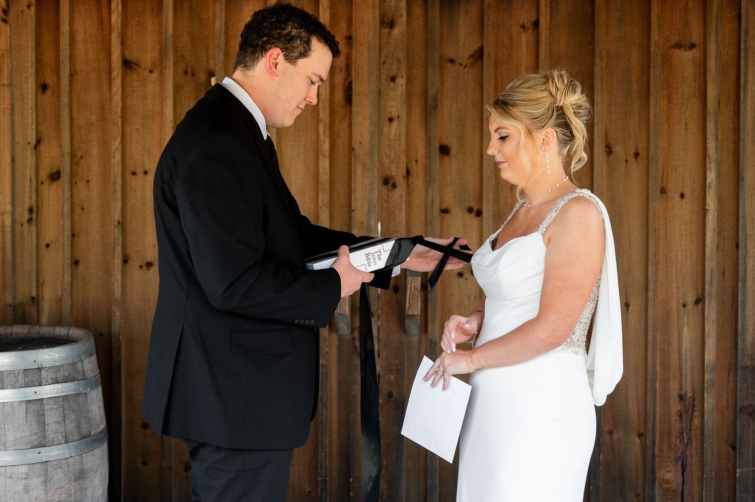 Emotional wedding moment between couple in rustic barn with wooden paneled walls.