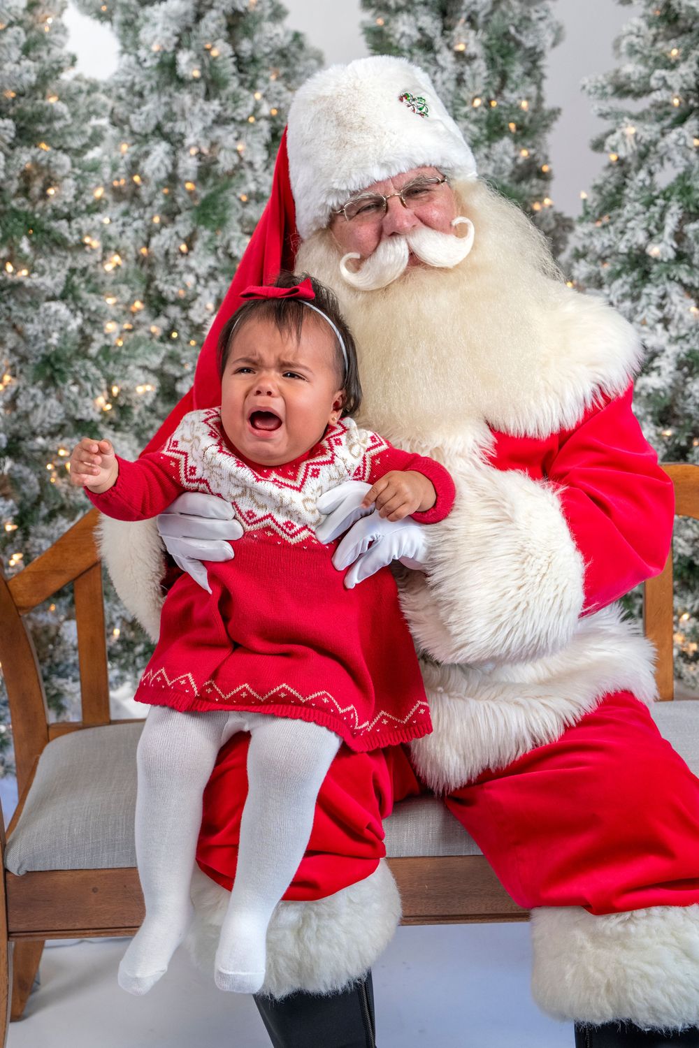 A sequence of photos showing a baby in a red dress having an emotional reaction while sitting with Santa Claus.