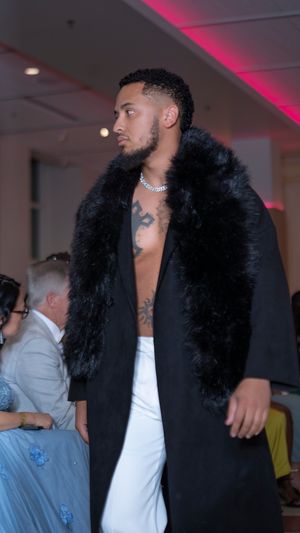 Black coat with dramatic fur collar styled with white top on fashion runway.