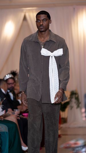 Gray corduroy outfit with white bow accent presented during fashion runway show.