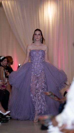 A lavender tulle evening gown with floral appliques walks the runway at a fashion show.