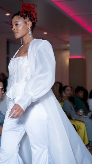 Fashion model walks runway in elegant white formal wear with dramatic puff sleeves and flowing design.