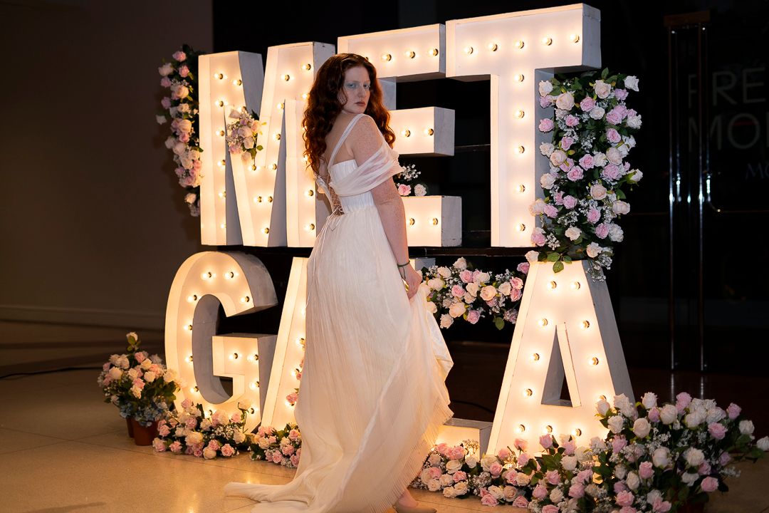 Models showcase elegant wedding gowns on a runway with floral decorations and illuminated letters in the background.