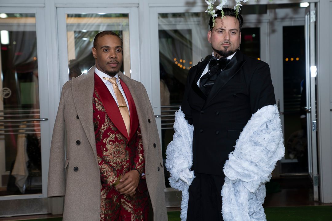 Models and attendees gather near entrance during formal fashion event.