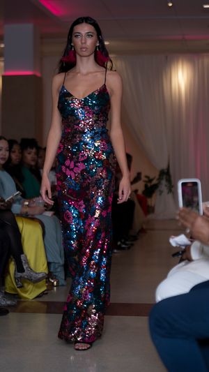 Sequined evening gown in blue and pink sparkles showcased on the runway.