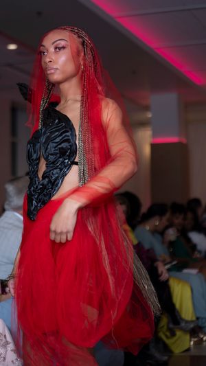 Dramatic red tulle gown with black accents presented on fashion runway.