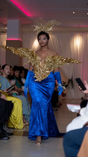 Royal blue velvet gown with gold wing-like accessories displayed during fashion show.