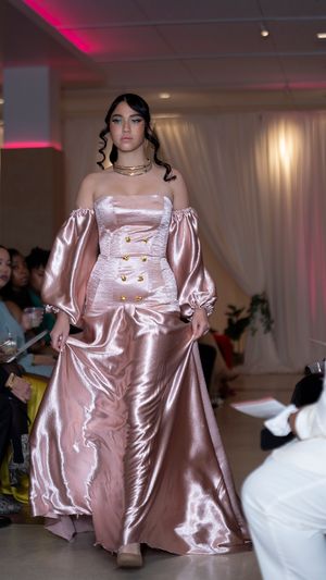 Rose gold satin gown with puff sleeves presented at fashion event.
