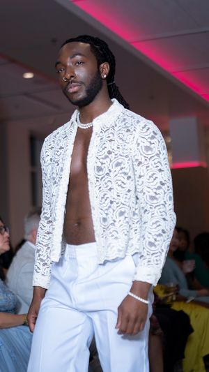 White lace bolero jacket paired with matching pants displayed during fashion show.