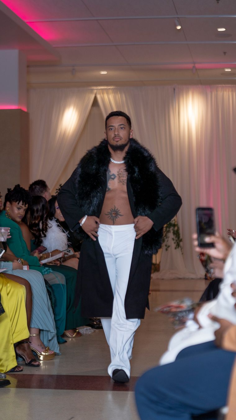 A performer in a black jacket and white pants dances energetically on stage during a wedding reception.