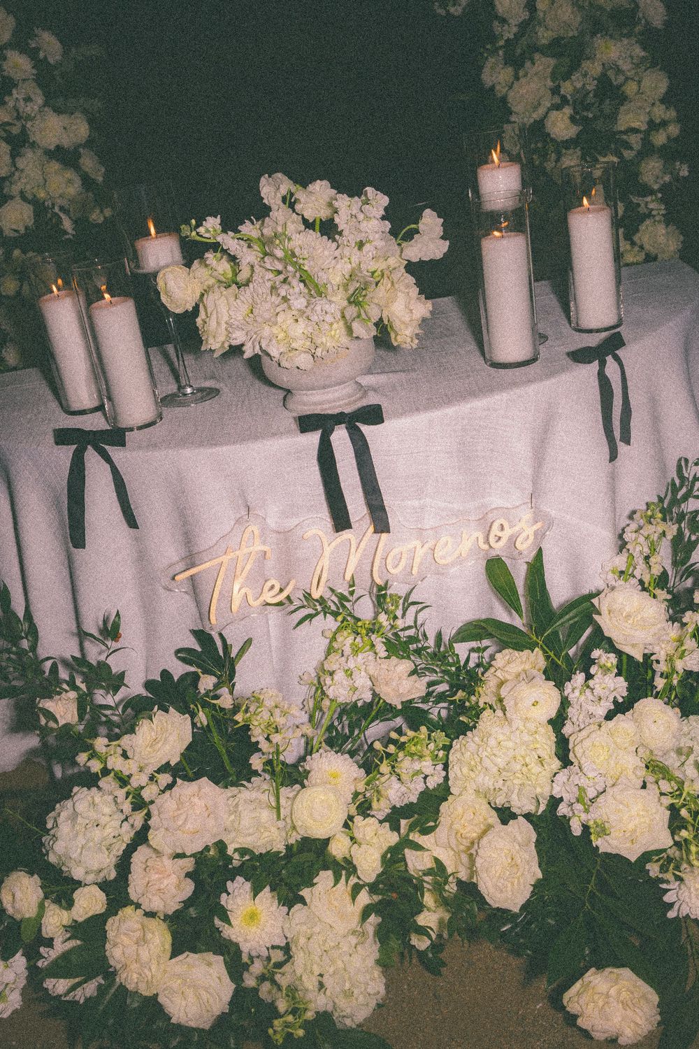 White hydrangeas and candles create an elegant wedding ceremony backdrop against a dark green wall.