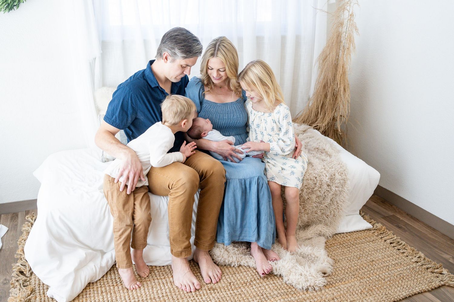 Family sitting together on a natural jute rug in a bright white room with soft neutral decor.