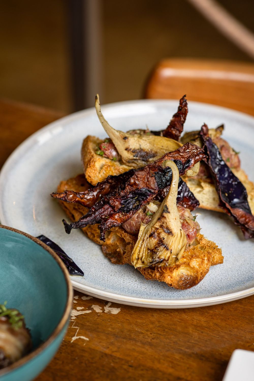 Grilled chicken wings with charred purple peppers and caramelized onions served on a white ceramic plate.