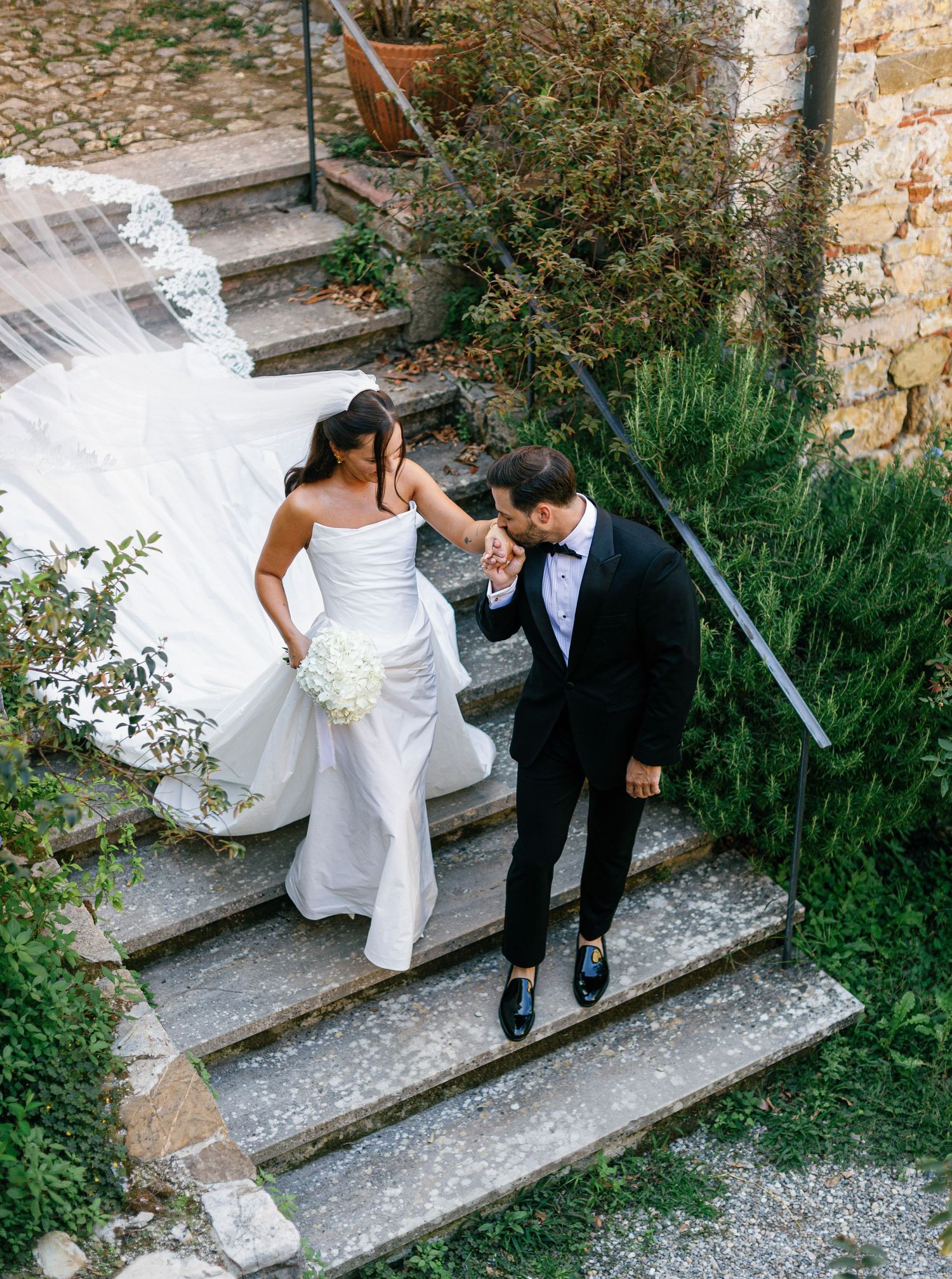 A couple in wedding attire descends stone steps together in a romantic sequence of candid moments.