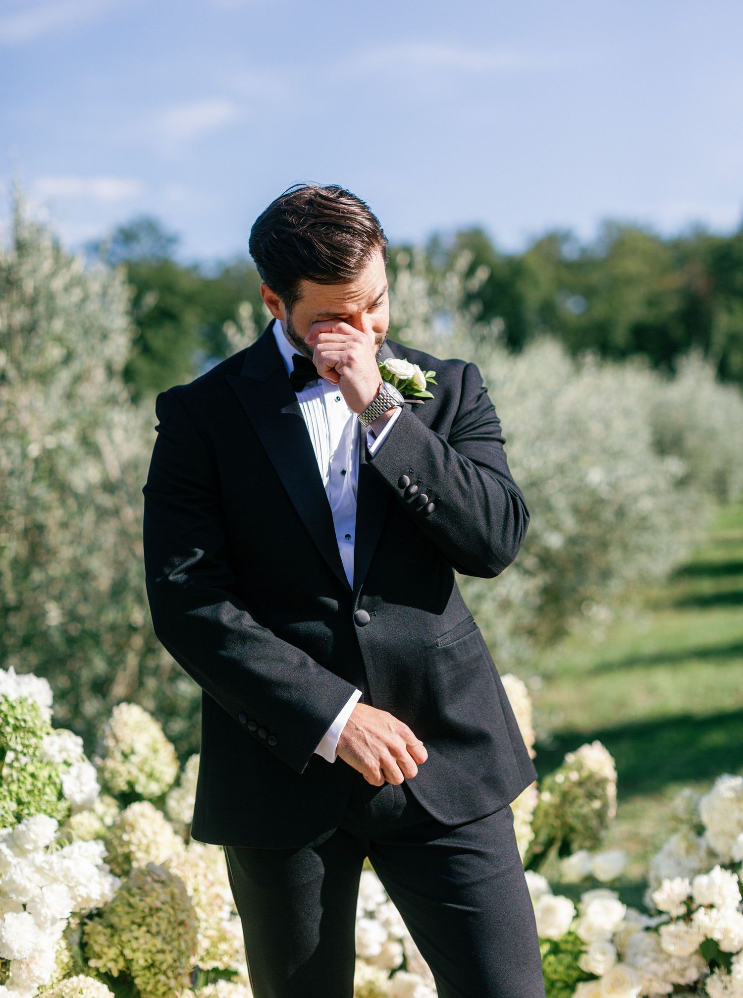 A formal event in an outdoor garden setting with flowering trees in the background.
