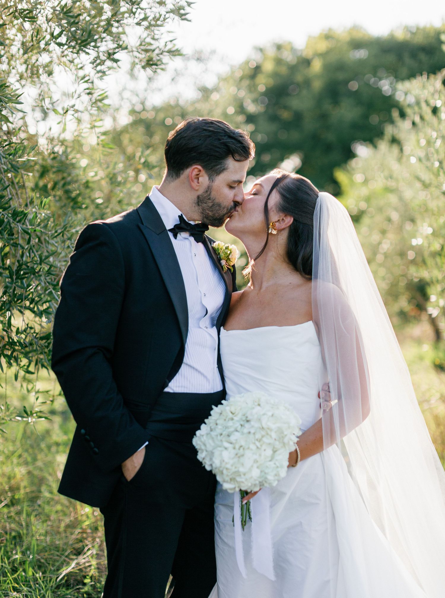 Romantic newlyweds share intimate moments in a garden setting during golden hour wedding photography session.