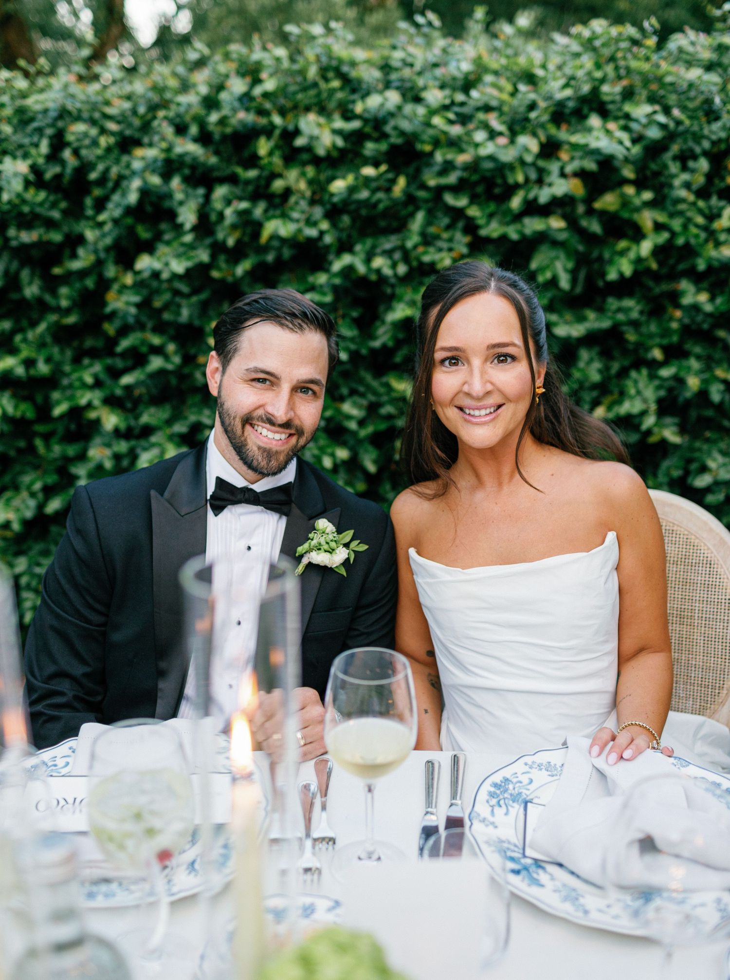 Newlyweds share candid moments at an outdoor wedding reception table with champagne and floral decorations.