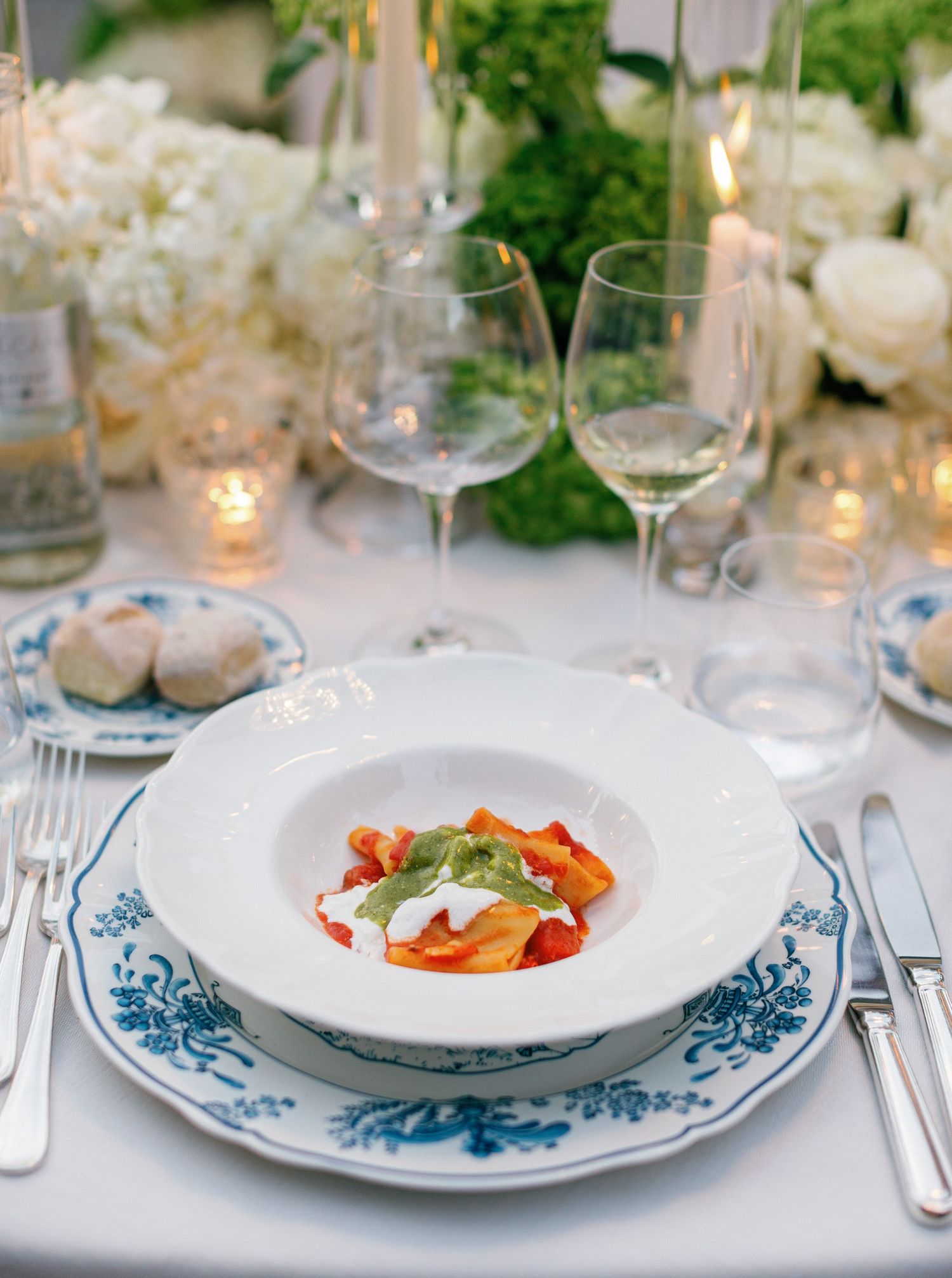 Elegant table settings with blue and white china plates, glassware, and soft candlelight create a romantic dining atmosphere.