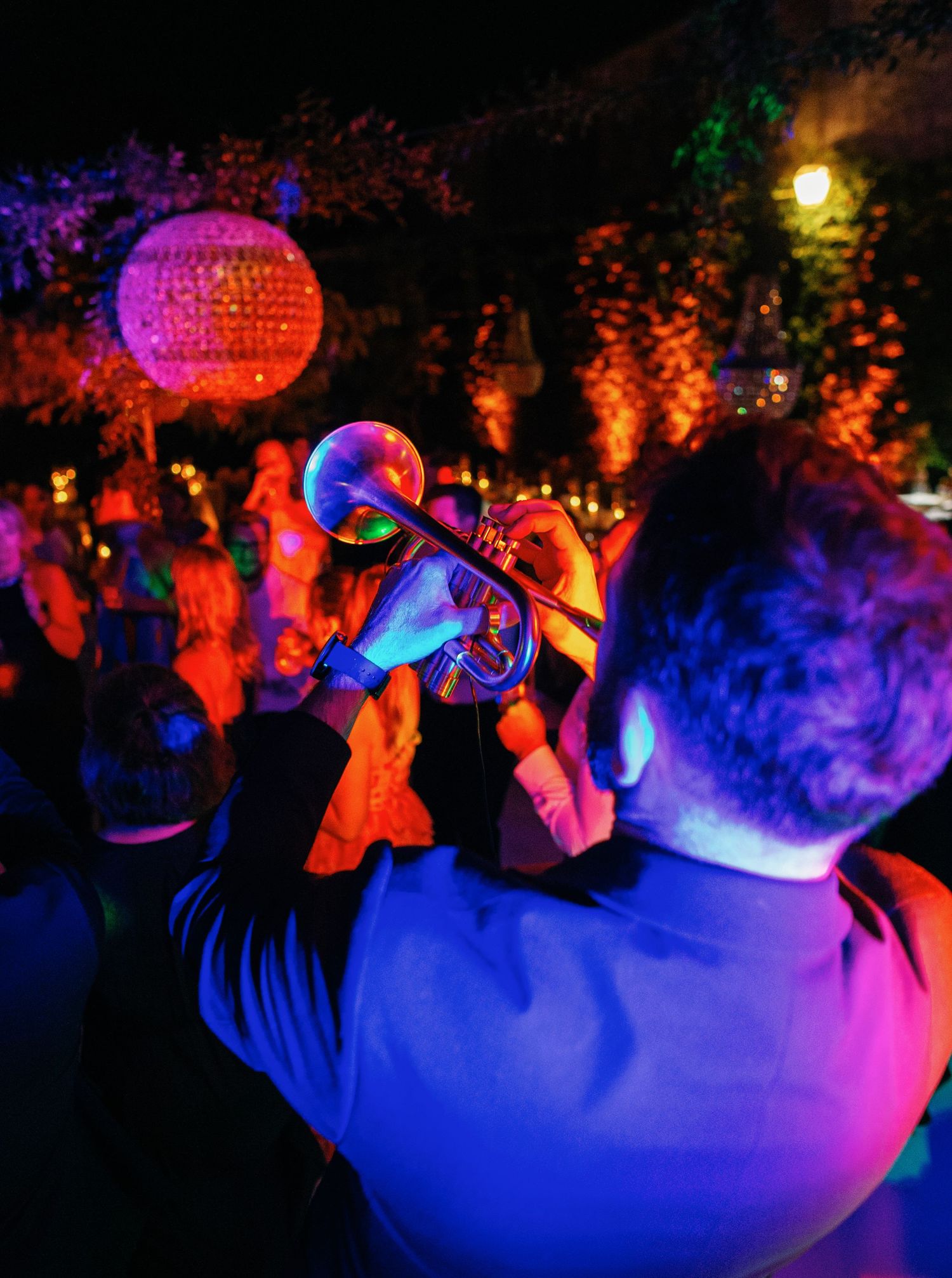 Dance floor crowd silhouetted against colorful disco lights and glowing decorations at a nightclub party.
