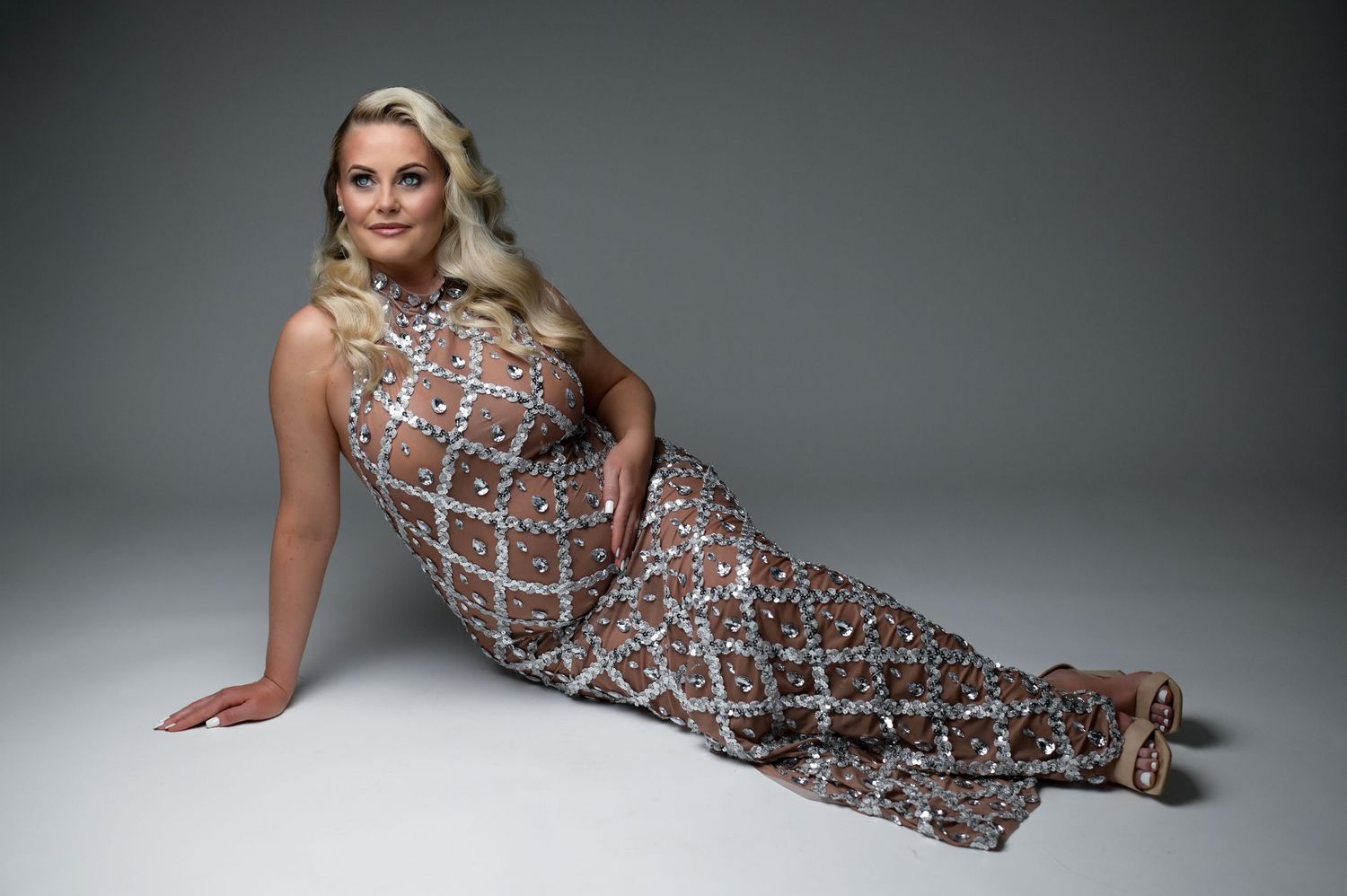 Model wearing a geometric patterned dress poses in various positions against a gray studio backdrop.