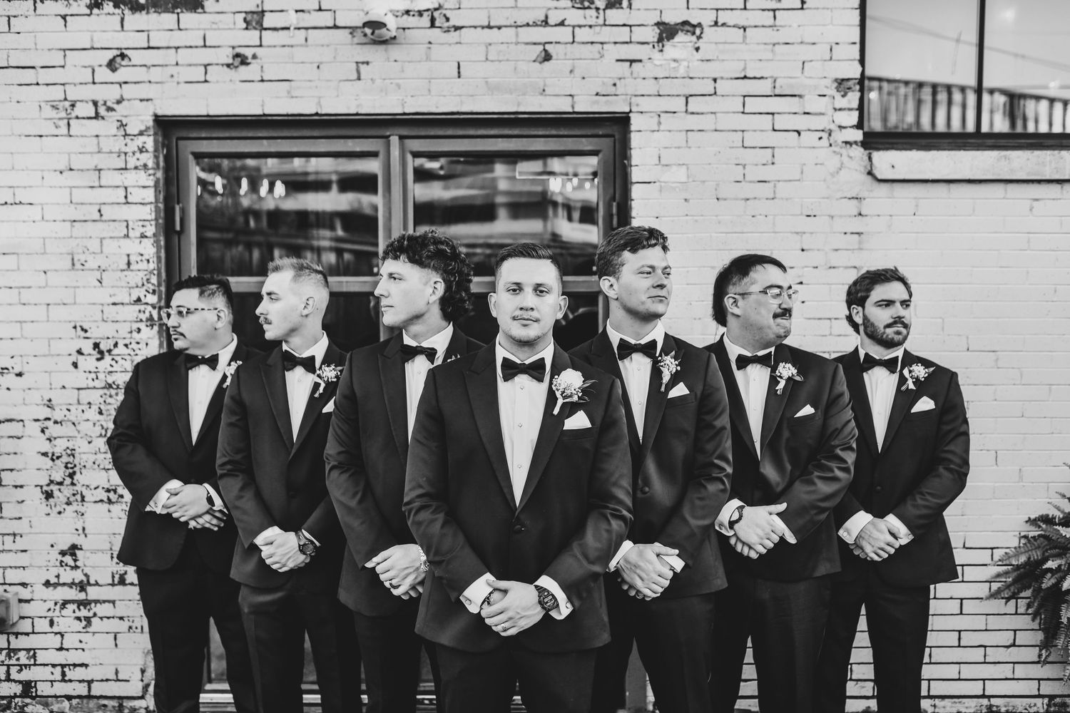Black-tie groom and groomsmen standing together in modern venue