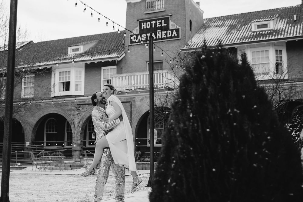 A vintage black and white photograph showing an old hotel building with people standing outside on the street.