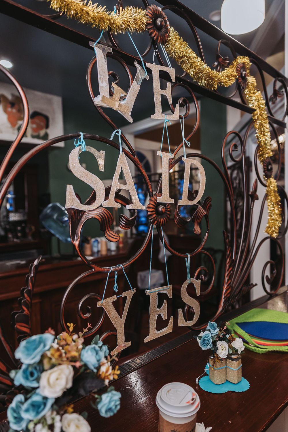 Decorative wedding signage reading 'WE SAID YES' adorned with gold tinsel and blue flowers.