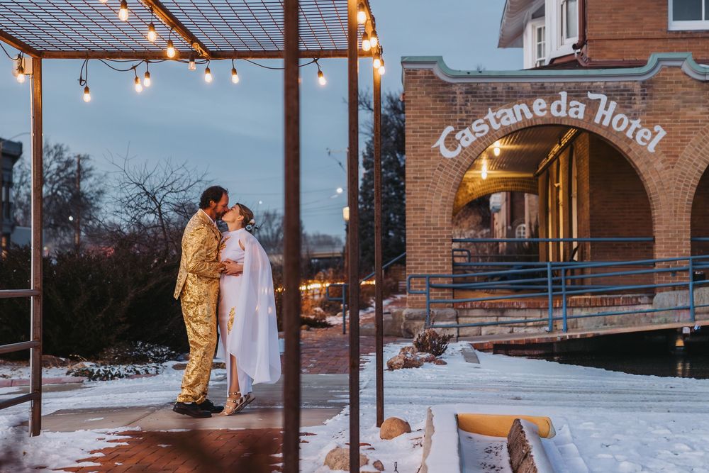 Couple embracing during their winter wedding at dusk with string lights illuminating the outdoor venue.