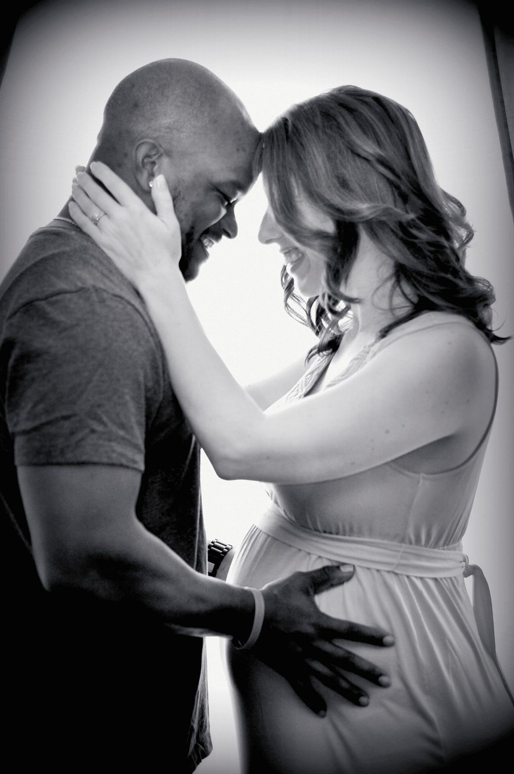 A romantic black and white portrait of an interracial couple sharing an intimate maternity moment in soft lighting. Napa, California