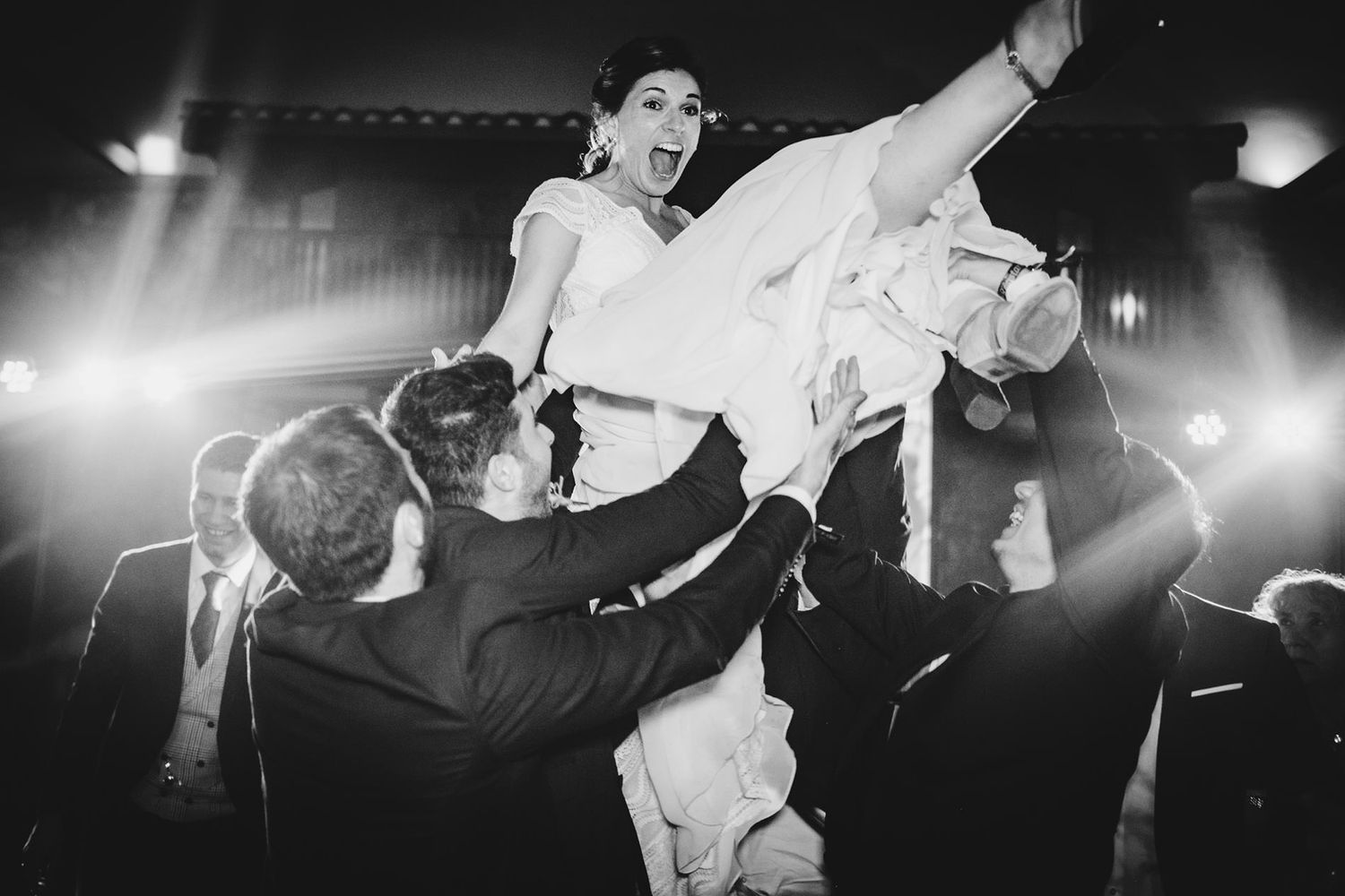 Novia siendo levantada en brazos por varios amigos mientras celebran en la pista de baile durante la fiesta de una boda en Asturias