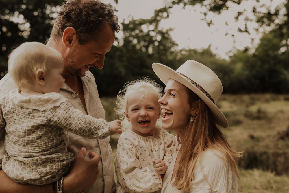 Laughing family with two toddlers enjoying a joyful outdoor moment in nature.