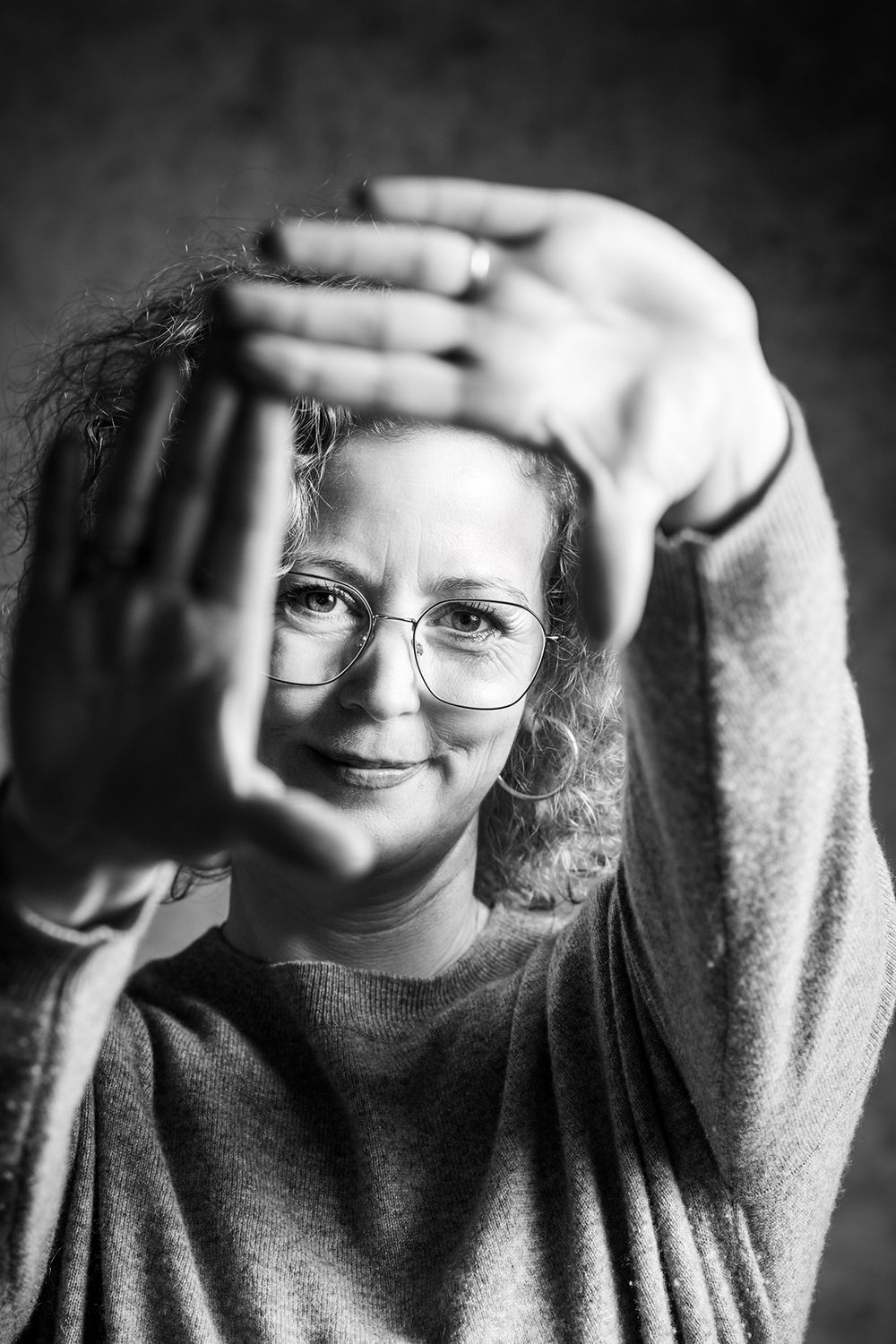 Portrait einer Frau, Hände nach vorne gestreckt, Gesicht dahinter, sie lächelt in die Kamera