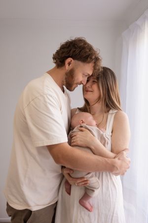 First time parents holding their baby and looking at each other during newborn session at Bishopdale studio