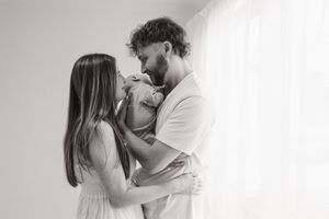 First time parents holding their baby and looking at each other during newborn session at Bishopdale studio