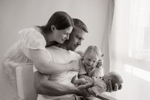 mum dad and sister looking at baby during newborn session at Bishopdale studio