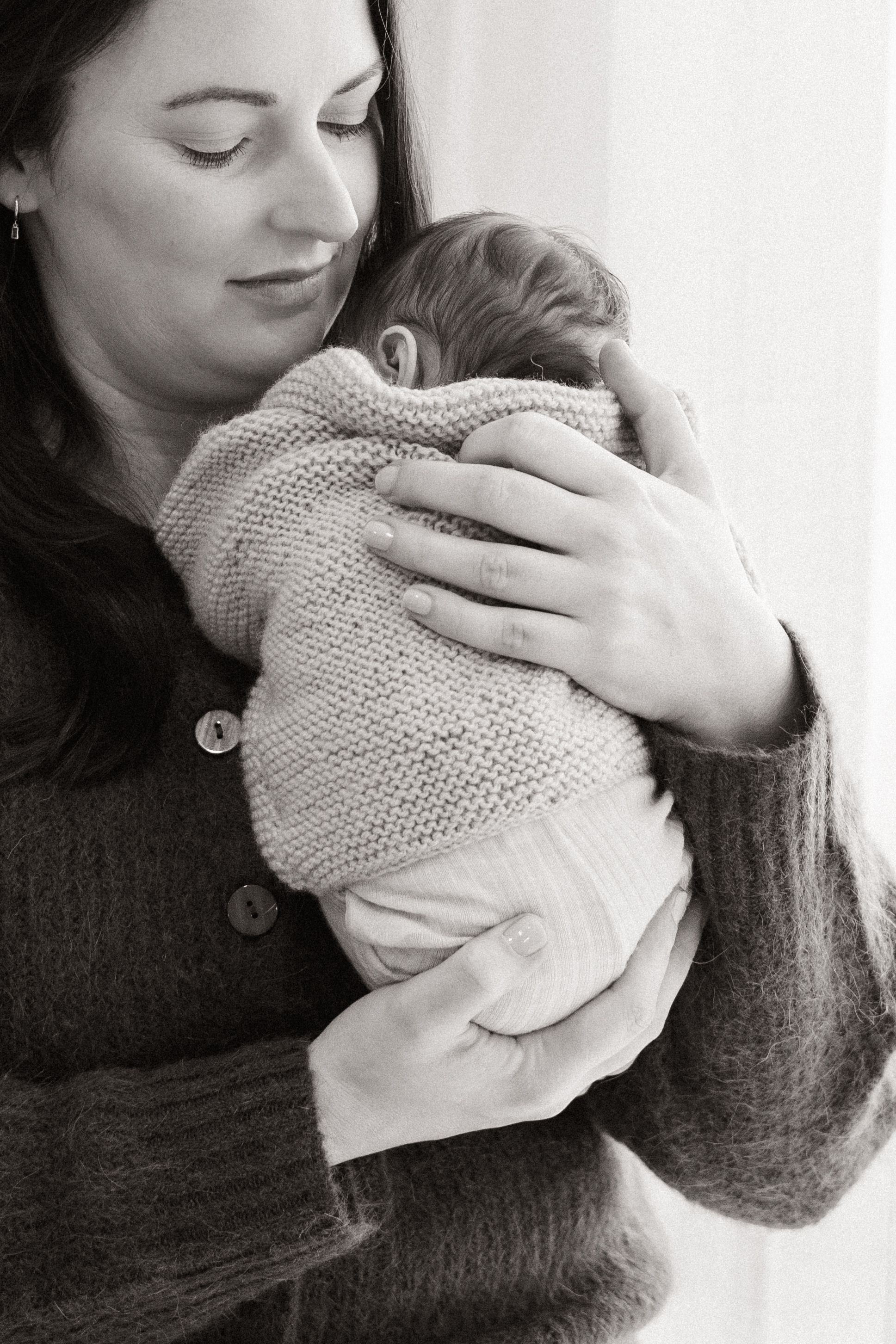 mum cuddling newborn baby close to her chest, during session in bishopdale studio