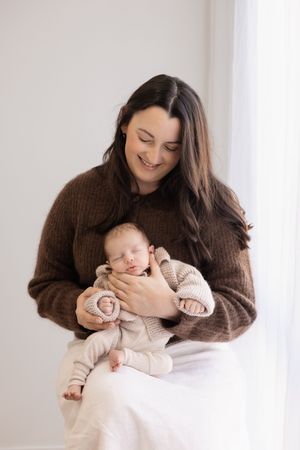 lifestyle newborn session in the studio, mum holding and looking at newborn
