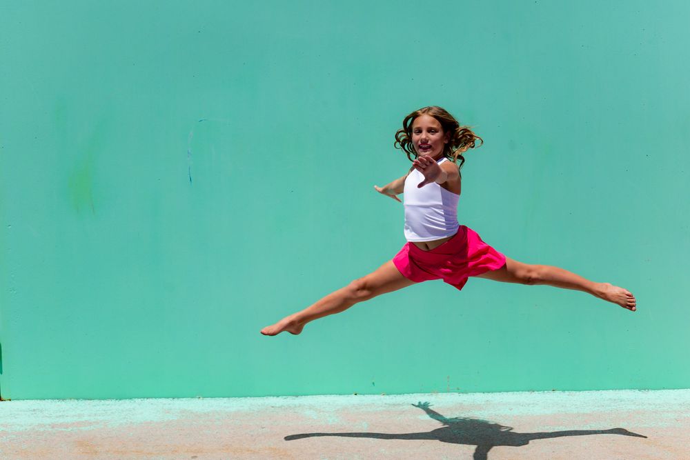 Leaping dancer photographed in sequence against turquoise wall.