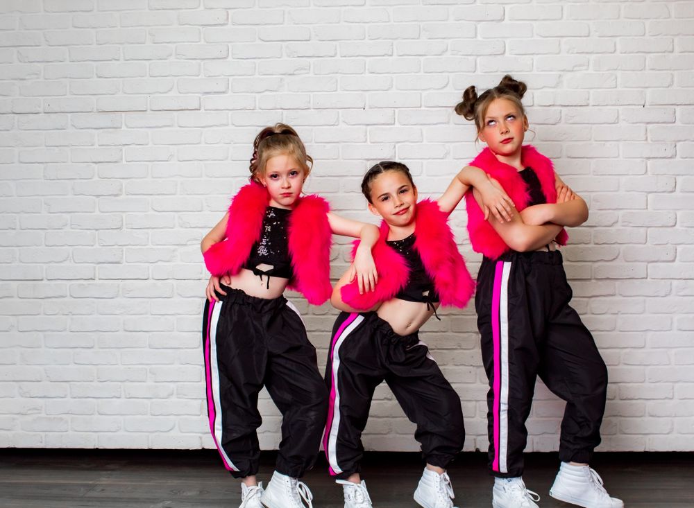 Group dance performance in coordinated pink and black outfits against white backdrop.
