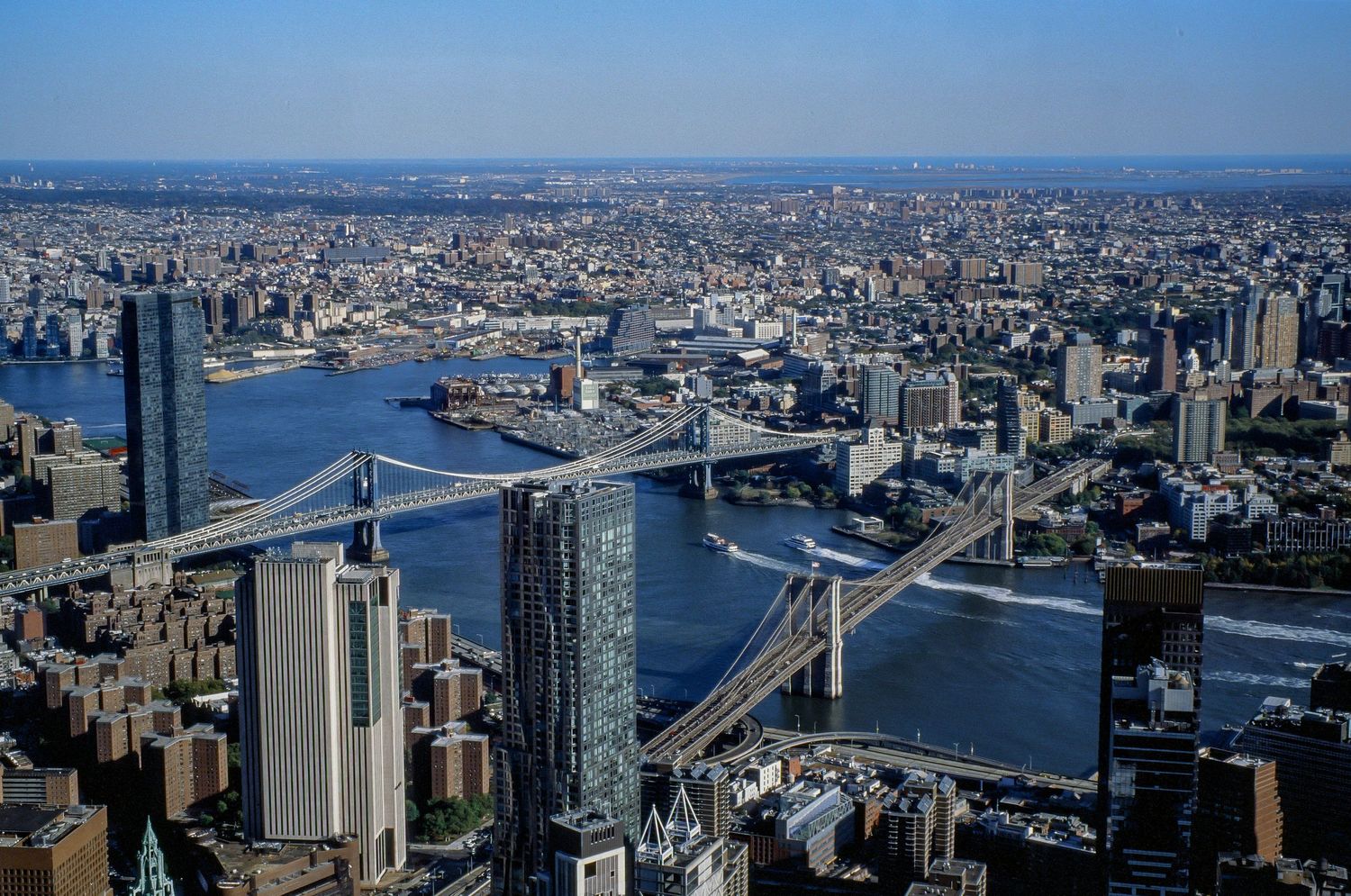 Aerial view of bridges spanning East River with Manhattan skyline in background.