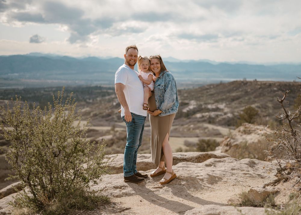 Couple sharing romantic moment on rocky desert overlook with mountain views.