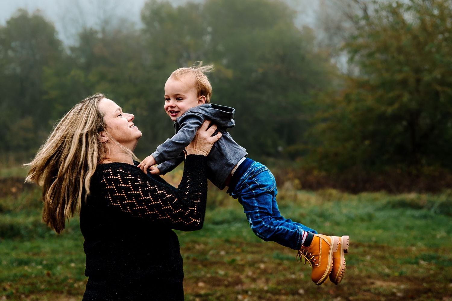 A parent and child share a joyful moment together while playing outdoors in an autumn setting.