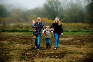 A group of people walk together through an autumn field on a misty afternoon.