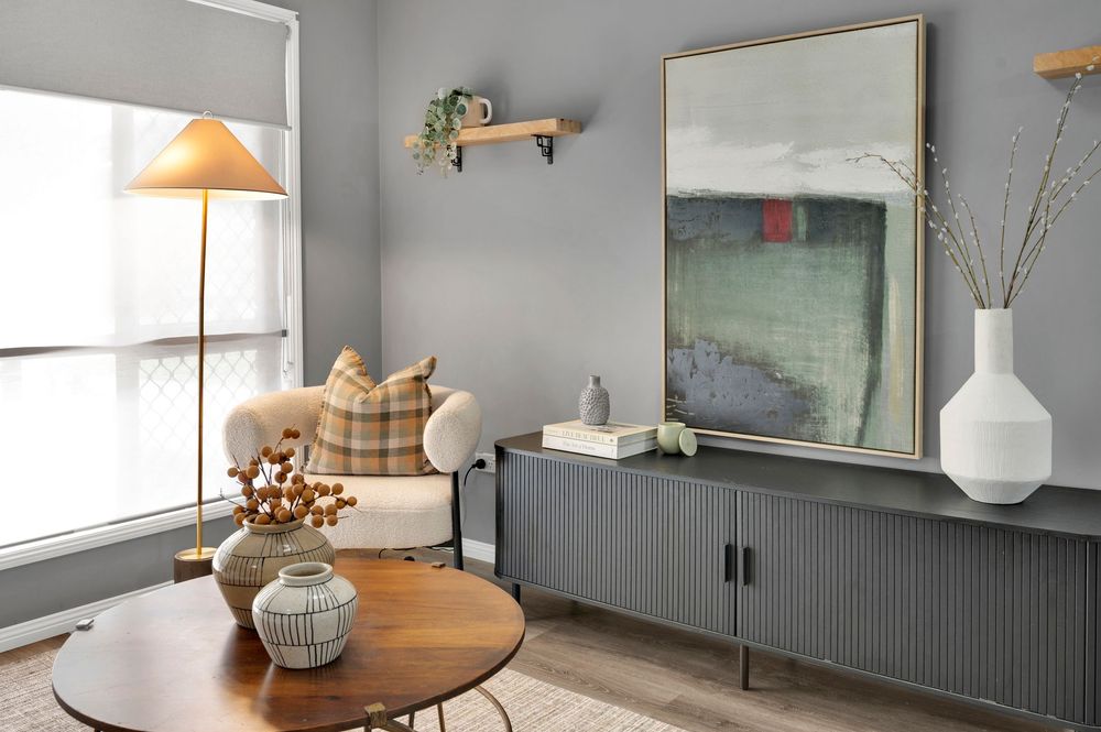 Modern farmhouse living room features neutral decor with wooden accents and soft gray walls for a cozy atmosphere.