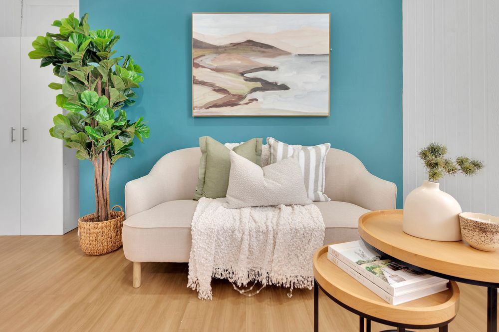 Coastal style living room with turquoise accent wall, white sofa, and natural decor elements.