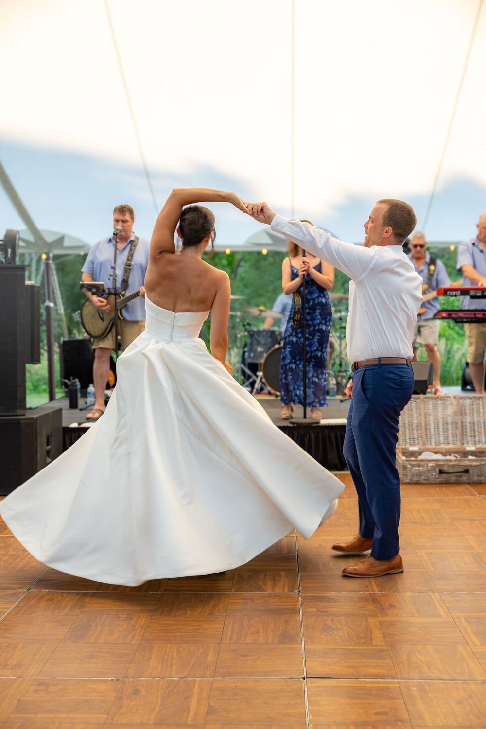 Bride and groom share first dance at wedding reception with live band performing in background.