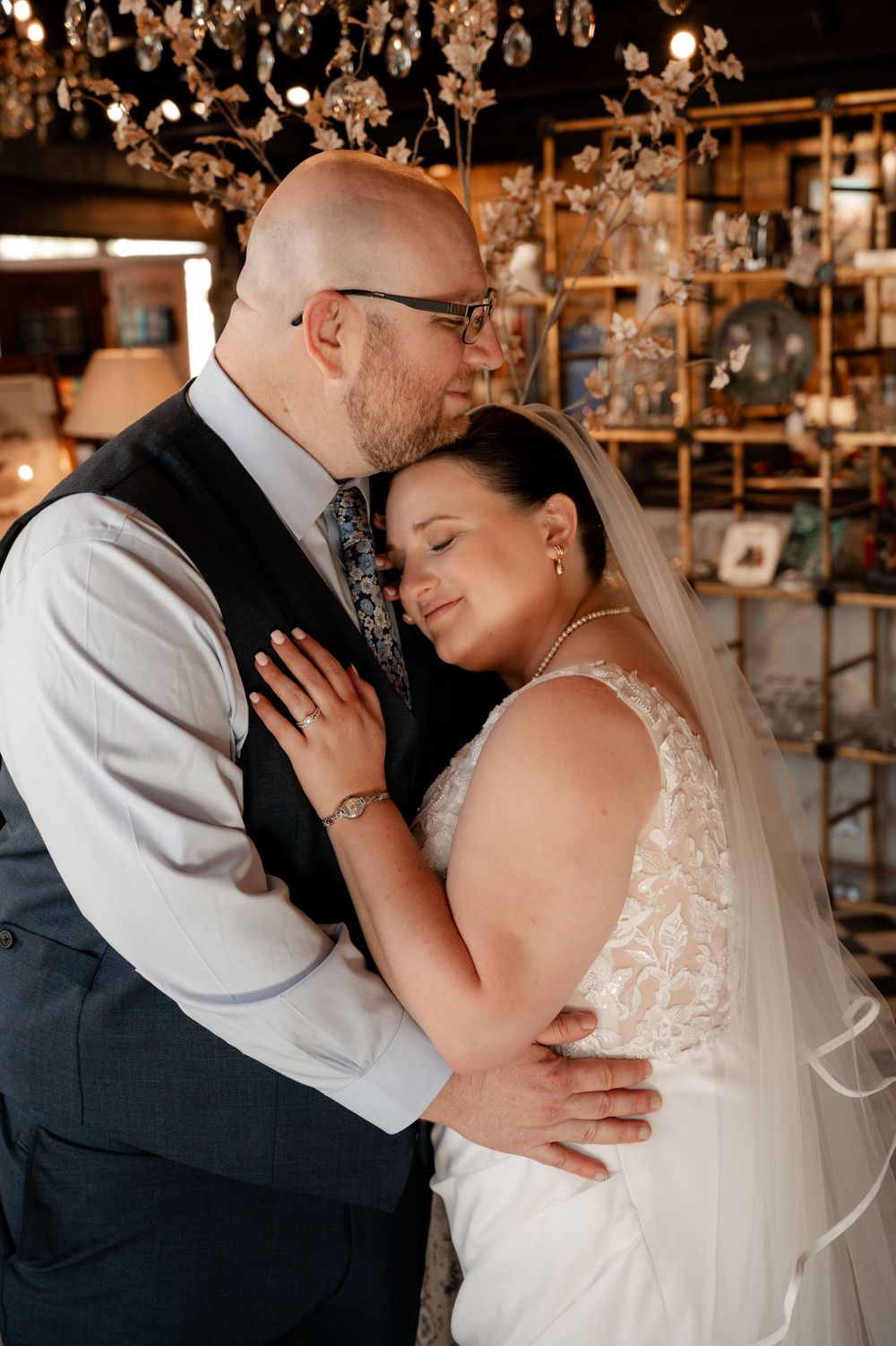 Bride and groom share an intimate embrace on their wedding day in a warmly decorated venue.