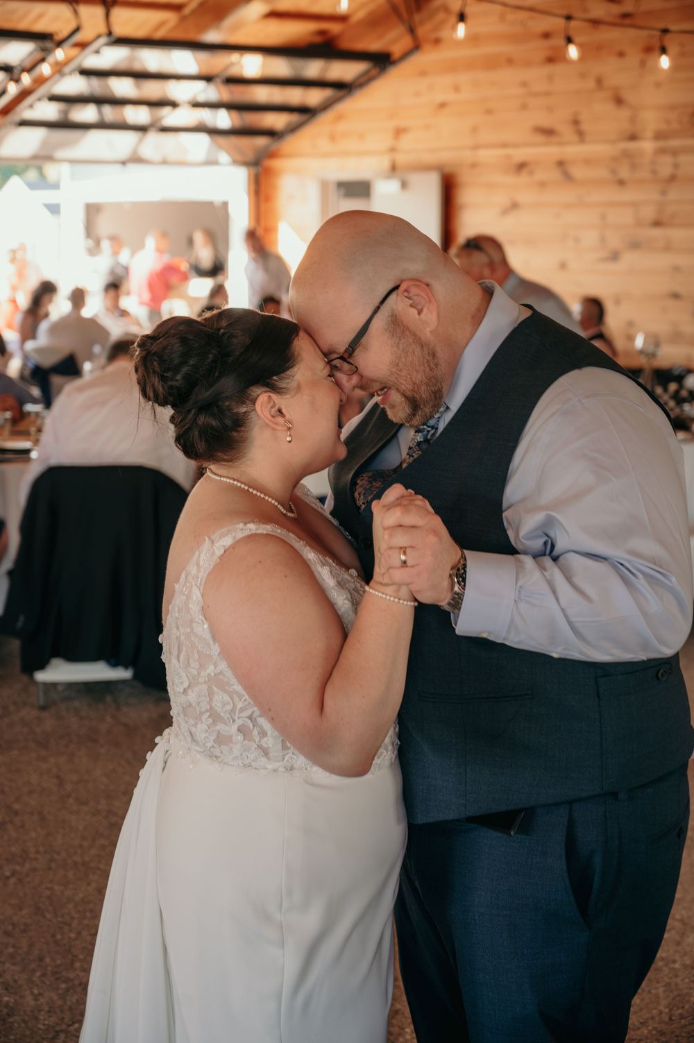 Bride and groom share a tender first dance in a rustic barn wedding reception venue.