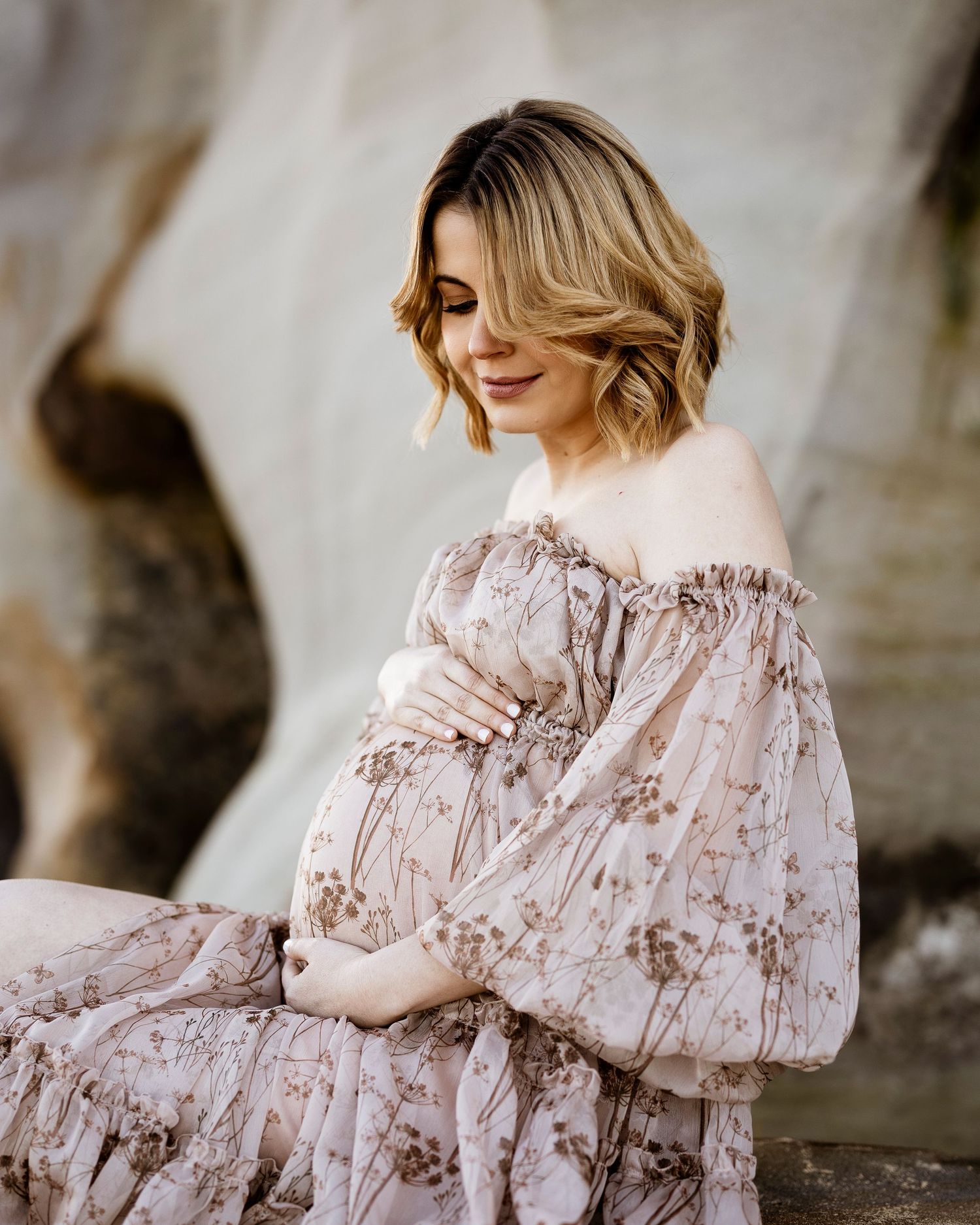 expecting mum in soft dress, holding her bump during sunset session
